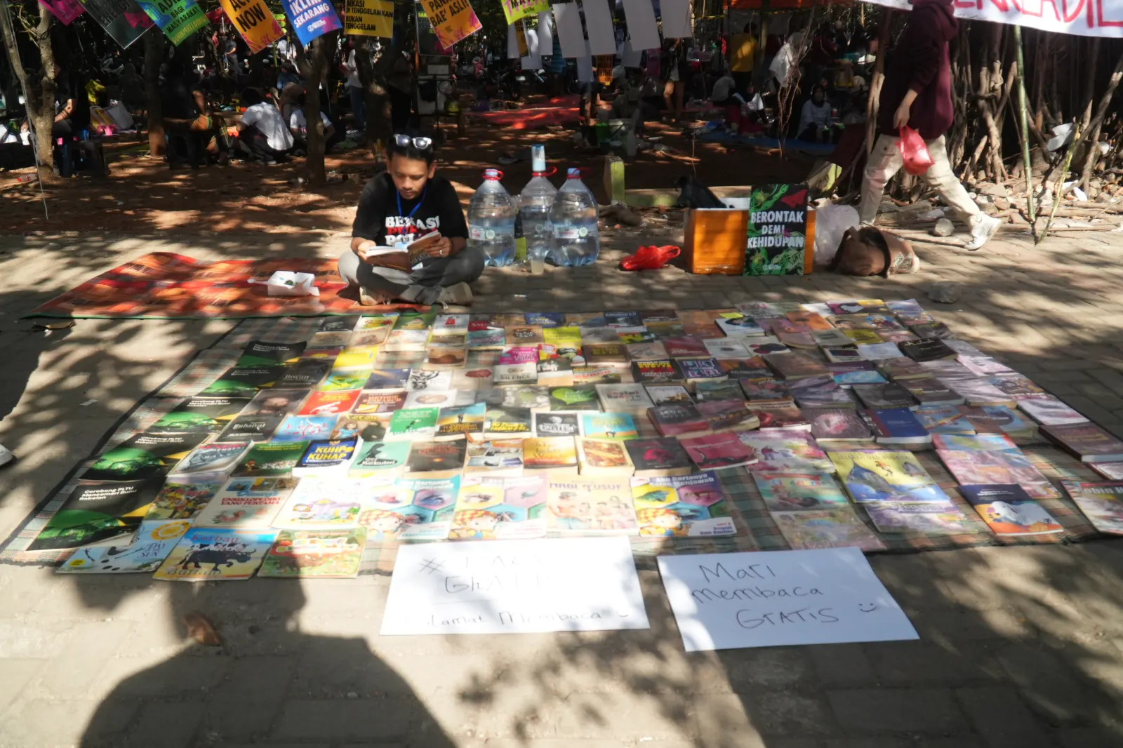Seorang laki-laki sedang membaca buku di lapak baca booth Bekasi Pukul Polusi.